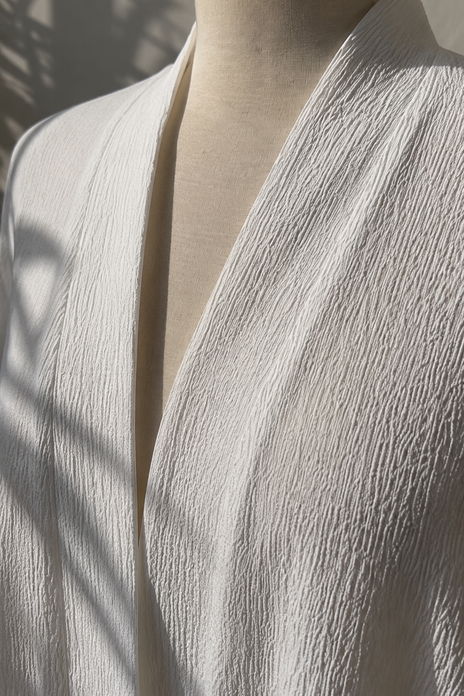 White textured abaya on a mannequin with a neutral background